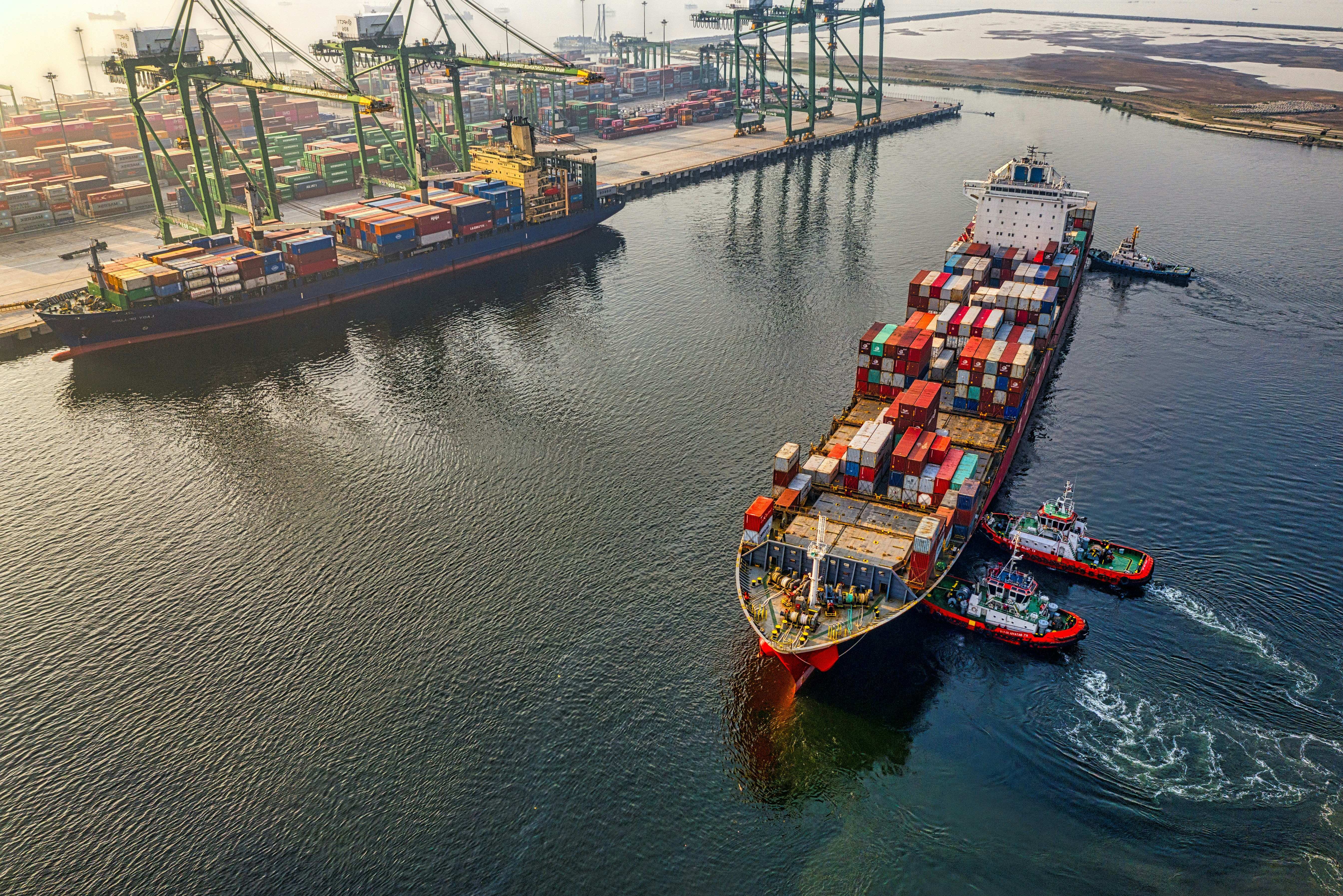 Loaded container vessel under tug escort alongside a terminal