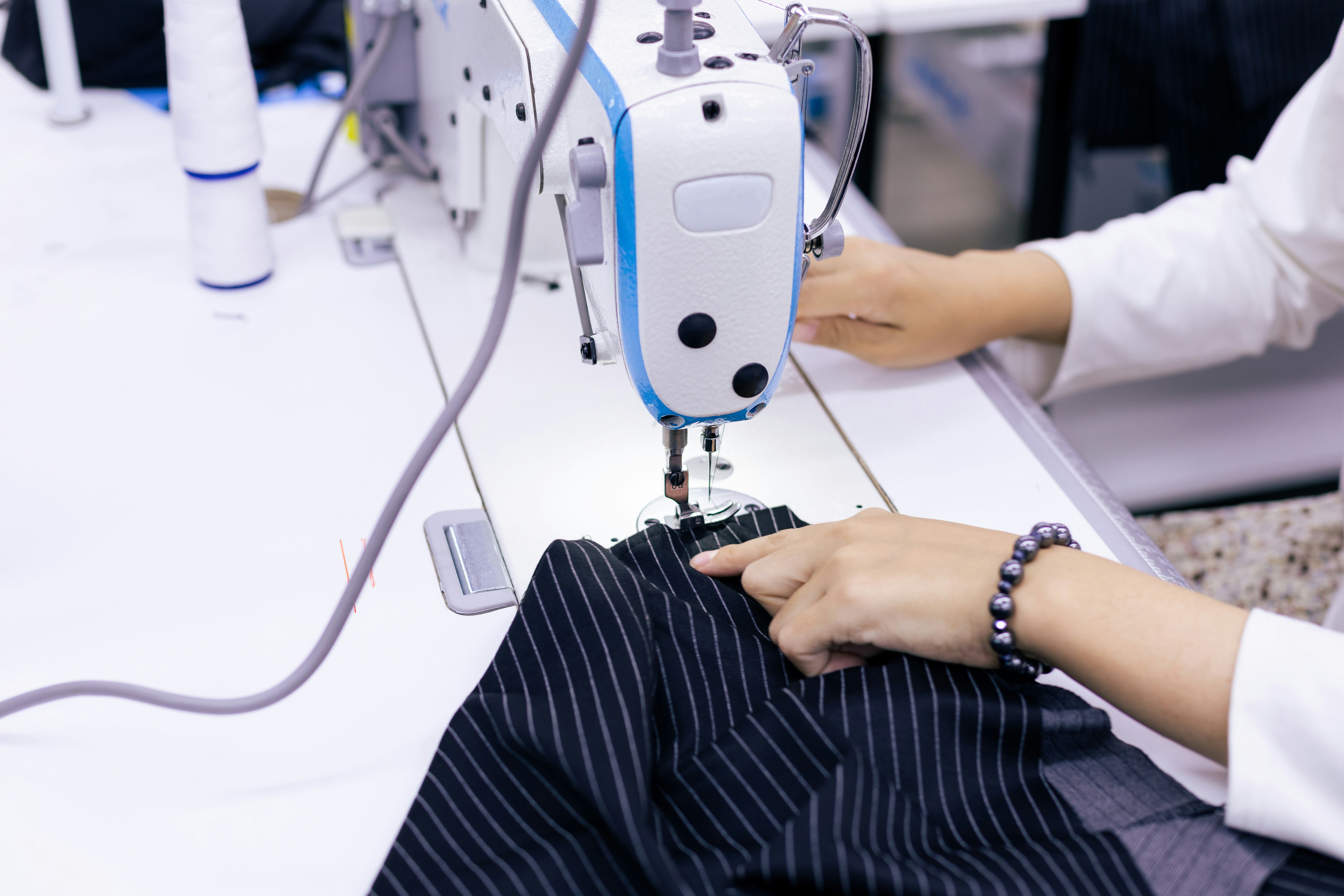 Machinist sewing a striped garment sample at an industrial machine